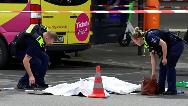 Police officers cover the body of a dead person at a cordoned-off area where a car ploughed into a crowd near Tauentzienstrasse in central Berlin, on June 8, 2022. One person was killed and eight injured when a car drove into a group of people in central Berlin on June 8, the fire service said. A police spokeswoman said the driver was detained at the scene after the car ploughed into a shop front along busy shopping street Tauentzienstrasse. It was not clear whether the crash was intentional. (Photo by John MacDougall/AFP Photo)