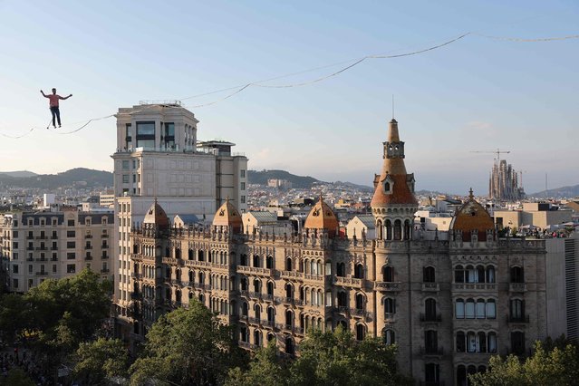 French tightrope walker and artist Nathan Paulin walks on a rope above the Plaza de Catalunya square in Barcelona, as part of the GREC festival, on July 2, 2023. (Photo by Lluis Gene/AFP Photo)