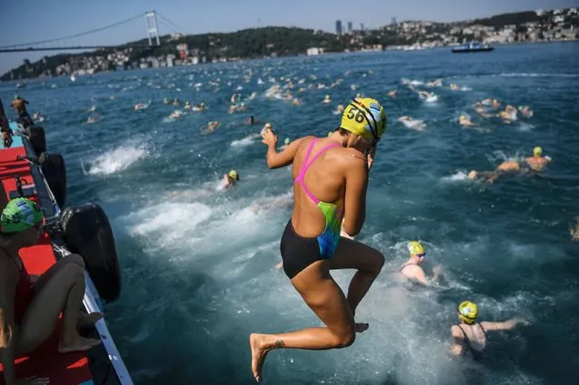 Swimmers jump in the Bosphorous river as they take part in the Bosphorus Cross Continental Swim event on July 23, 2017. The race takes participants 6 kms down the Bosphorus Strait from the Asian side of Istanbul to the European side. (Photo by Ozan Kose/AFP Photo)
