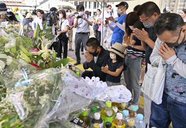 People pray at a makeshift memorial near the scene where the former Prime Minister Shinzo Abe was shot while delivering his speech to support the Liberal Democratic Party's candidate during an election campaign in Nara, Saturday, July 9, 2022.  Abe, a divisive arch-conservative and one of his nation's most powerful and influential figures, has died after being shot during a campaign speech Friday in western Japan, hospital officials said. (Photo by Kyodo News via AP Photo)