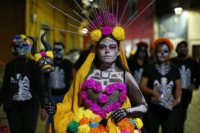 A woman dressed as a catrina participates during the parade of the “Day Of The Dead Festival” in Guanajuato as part of the 2021 'Day of The Dead' celebration on November 1, 2021 in Guanajuato, Mexico. Considered one of the most popular celebrations in Mexico, the Day of the Dead takes place every year on November 1 and 2. People remember those who have died with offerings, family gatherings and visits to their graves. The celebration has expanded to other countries in Latin America and the rest of the world. After the 2020 restrictions due to the Covid-19 pandemic, this year Mexican authorities will allow people to visit cemeteries by following protocols. (Photo by Leopoldo Smith/Getty Images)