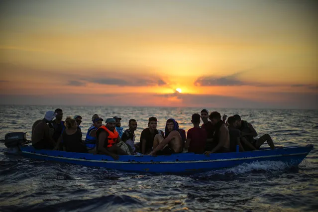 Migrants from Tunisia sail in a wooden boat as they are assisted by crew members of the Spanish NGO Open Arms, sixteen miles west of the Italian island of Pantelleria in the Mediterranean sea, on Friday, August 5, 2022. The NGO searched and assisted 20 people in a precarious wooden boat before they were rescued by the Italian coast guard. (Photo by Francisco Seco/AP Photo)