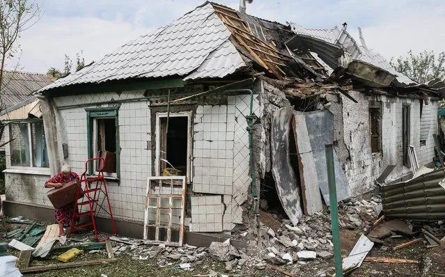 A woman collects belongings from her damaged home, in Khartsyzk, about 24 kms from Donetsk, Ukraine, 18 August 2014. (Photo by Sergei Ilnitsky/EPA)