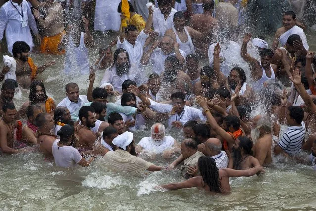 Indian Sadhus, or Hindu holy men, surround their guru, center, during a bath in the Godavari River during Kumbh Mela, or Pitcher Festival in Nashik, India, Saturday,  August 29, 2015. (Photo by Tsering Topgyal/AP Photo)