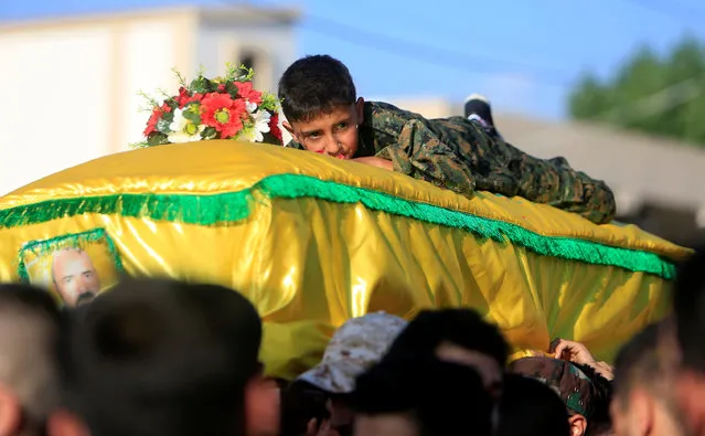 Son of Omar al-Obeid, a Lebanon's Hezbollah member who was killed fighting alongside Syrian army forces in Syria, lies on his coffin during his funeral in Doueir village, near Nabatieh in southern Lebanon, July 5, 2016. (Photo by Ali Hashisho/Reuters)