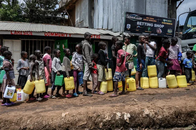 Children queue with their jerrycans to fill them with free water distributed by the Kenyan government at Kibera slum in Nairobi, Kenya, on April 7, 2020. President Kenyatta announced the distribution of free water to low income communiites to curb the spread of the COVID-19 Coronavirus. (Photo by Gordwin Odhiambo/AFP Photo)