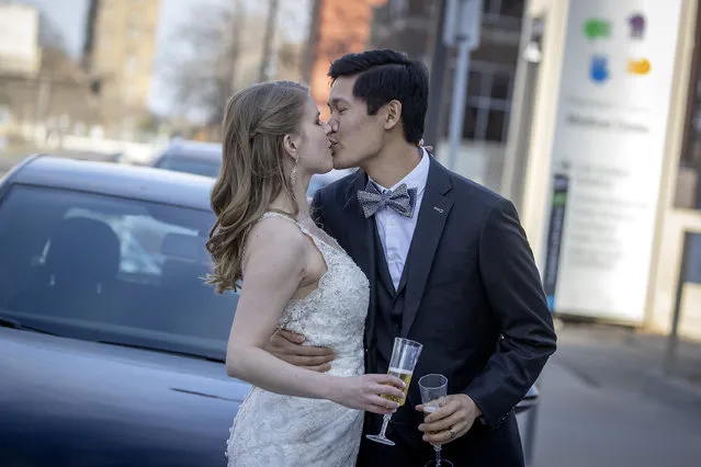 Kelsey and Alex Lee jumped out of their car to share a toast with co-workers from the Hennepin Healthcare's physical therapy department on the sidewalk after they were married, Friday, April 10, 2020, in Minneapolis. The wedding did not go exactly as they planned; there were only two witnesses and the officiant in attendance. Instead of a banquet, Alex Lee picked up takeout and they drove home to their apartment in Hopkins. (Photo by Elizabeth Flores/Star Tribune via AP Photo)