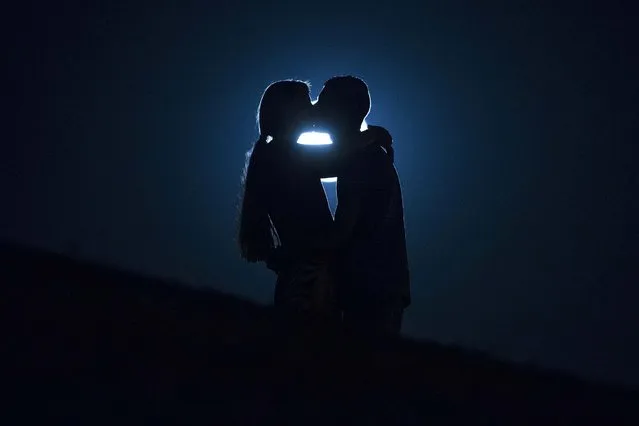 A perigee moon, also known as a supermoon, rises in the sky as a couple kiss in Madrid Spain, Tuesday September 9, 2014. The phenomenon, which scientists call a “perigee moon”, occurs when the moon is near the horizon and appears larger and brighter than other full moons. (Photo by Andres Kudacki/AP Photo)
