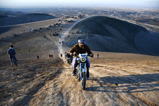 Afghan men show their skills as they ride motorcycles along a hillside on the outskirts of Mazar-i-Sharif on January 24, 2025. (Photo by Atif Aryan/AFP Photo)