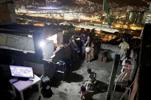 2016 Rio Olympics, Opening Ceremony, Maracana, Rio de Janeiro, Brazil on August 5, 2016. A family stands on the roof of their home in the Mangueira favela, or slum, as a television broadcasts the Olympic opening ceremony. (Photo by Ricardo Moraes/Reuters)