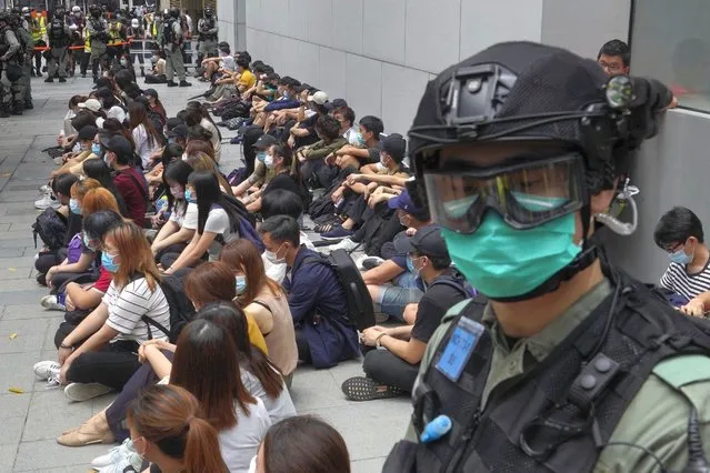 Hong Kong riot police guard arrested anti-government protesters in the Central district of Hong Kong, Wednesday, May 27, 2020. Hong Kong police massed outside the legislature complex Wednesday, ahead of debate on a bill that would criminalize abuse of the Chinese national anthem in the semi-autonomous city. (Photo by Vincent Yu/AP Photo)