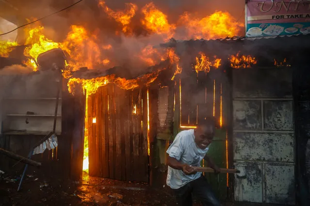 A man reacts as he battles a huge fire engulfed a small market in Kawangware slum in Nairobi, Kenya, 27 October 2017. A small shop allegedly owned by a member of Kikuyu community, a tribe which President Uhuru Kenyatta belongs to, was set ablaze by supporters of the opposition coalition the National Super Alliance (NASA) and its presidential candidate Raila Odinga during a riot. The fire spread, burning down nearby shops together. Kenya's election commission Independent Electoral and Boundaries Commission (IEBC) on 27 October called off repeat presidential poll in four counties indefinitely. (Photo by Dai Kurokawa/EPA/EFE)