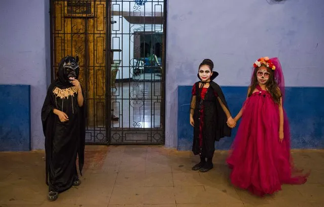 Three children costumes as witches and demons pose on a street during the celebration of the “Los Agüizotes” in Masaya, Nicaragua, 27 October 2017. (Photo by Jorge Torres/EPA/EFE)