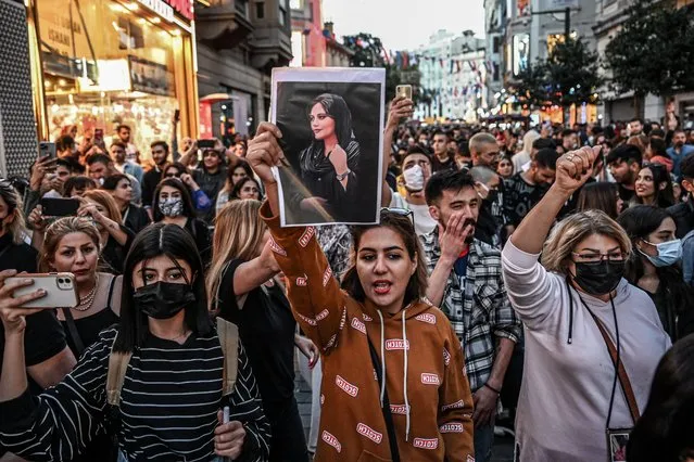 A protester holds a portrait of Mahsa Amini during a demonstration in support of Amini, a young Iranian woman who died after being arrested in Tehran by the Islamic Republic's morality police, on Istiklal avenue in Istanbul on September 20, 2022. Amini, 22, was on a visit with her family to the Iranian capital when she was detained on September 13 by the police unit responsible for enforcing Iran's strict dress code for women, including the wearing of the headscarf in public. She was declared dead on September 16 by state television after having spent three days in a coma. (Photo by Ozan Kose/AFP Photo)