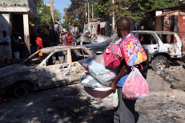 A man carrying his belongings observes the wreckages of vehicles burnt over the weekend by armed gangs, many grouped behind an alliance known as Viv Ansanm, as he flees the Poste Marchand suburb, in Port-au-Prince, Haiti on December 9, 2024. (Photo by Ralph Tedy Erol/Reuters)