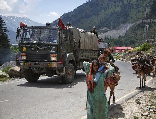 Kashmiri Bakarwal nomads walk as an Indian army convoy moves on the Srinagar- Ladakh highway at Gagangeer, north-east of Srinagar, India, Wednesday, June 17, 2020. Indian security forces said neither side fired any shots in the clash in the Ladakh region late Monday that was the first deadly confrontation on the disputed border between India and China since 1975. China said Wednesday that it is seeking a peaceful resolution to its Himalayan border dispute with India following the death of 20 Indian soldiers in the most violent confrontation in decades. (Photo by Mukhtar Khan/AP Photo)