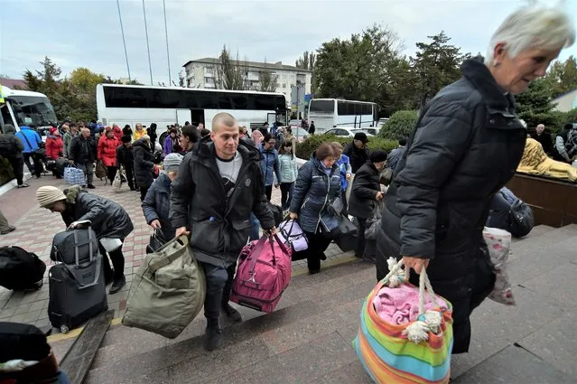 Evacuees from Kherson gather upon their arrival at the railway station in Dzhankoi, Crimea, on October 21, 2022. Russian authorities, who initially dismissed talk of evacuating the city, sharply changed course this week, warning that Kherson could come under massive Ukrainian shelling and encouraging residents to leave – but only to Russian-held areas. Ukrainian forces pressing an offensive in the south have zeroed in on Kherson, a provincial capital that has been under Russian control since the early days of the invasion. (Photo by AP Photo/Stringer)