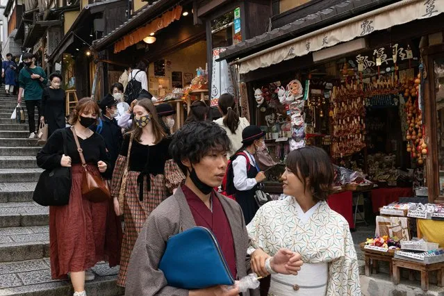 People walk down a shopping street in a touristy section of Kyoto on October 11, 2022. (Photo by Fred Mery/AFP Photo)