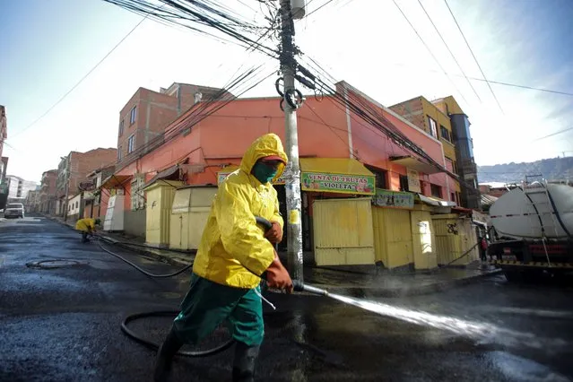 Man wearing safety suit sprays water at the entrance of Haití Market, where a meat vendor who died of Covid-19 worked on June 23, 2020 in La Paz, Bolivia. According to World Health Organization, Bolivia has over 25,000 positive cases of coronavirus (COVID-19) and 820 deaths. There is concern about a possible collapse of the healthcare system. (Photo by Gaston Brito/Getty Images)