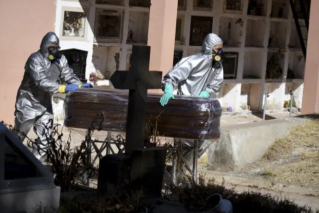 A coffin holding the remains of Cristobal Huanca Mendoza is guided by workers through a cemetery to a common grave area, in Cochabamba, Bolivia, Thursday, July 2, 2020. The coffin of Mendoza, who died Sunday in Cochabamba, is wrapped in plastic as is common by funeral homes when working with COVID-19 victims or suspected victims of the new coronavirus. (Photo by Dico Soliz/AP Photo)