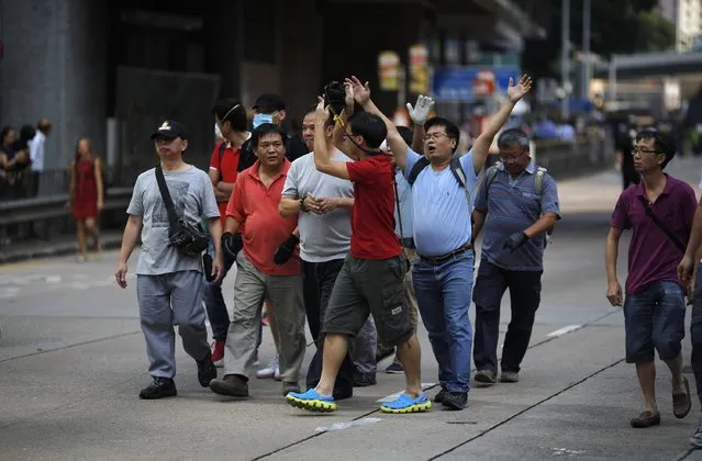 Anti-Occupy protesters block a photographer taking pictures of fellow anti-Occupy demonstrators removing barricades and tents (obscured) at the main protest site in Admiralty in Hong Kong October 13, 2014. (Photo by Carlos Barria/Reuters)