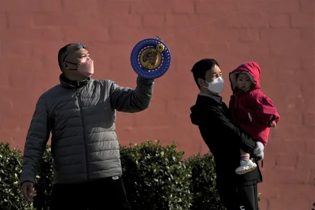 A man carries a child watch a resident flies a kite at a park in Beijing, Sunday, November 27, 2022. (Photo by Andy Wong/AP Photo)