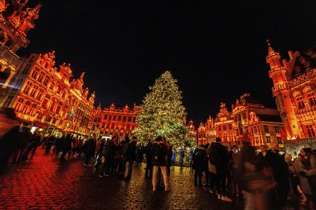 Visitors stand in front of the illuminated Christmas tree at the Winter Wonder and Christmas Market on the Grand Place in Brussels, Belgium, November 25, 2022. (Photo by Olivier Matthys/AP Photo)