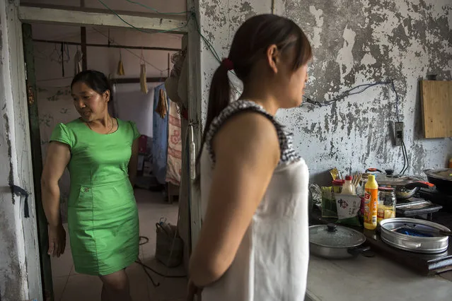 Members of the Zhong family stand in their kitchen in Baodi, China on May 22, 2016. The Zhongs migrated to the Beijing area from an impoverished area of Guizhou province. They arrived in Beijing and heard that there was work to be had demolishing homes in Baodi. Baodi, like many of the capital's surrounding villages, is being transformed into a satellite city of residential blocks and apartment towers. (Photo by Michael Robinson Chavez/The Washington Post)
