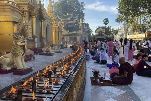 Buddhist devotees and monks pray at the popular Shwedagon pagoda during the full moon day of Thadingyut, the lighting festival to mark the end of Buddhist Lent, Sunday, October 9, 2022, in Yangon, Myanmar. The Thadingyut festival is held at the end of Buddhist Lent marking Buddha's descent from heaven after he sermonized the Abhidamma to his mother who was born in heaven. (Photo by Thein Zaw/AP Photo)