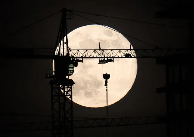 The last full moon of the year, known as the cold moon, rises behind a construction site in Ankara on December 8, 2022. (Photo by Adem Altan/AFP Photo)