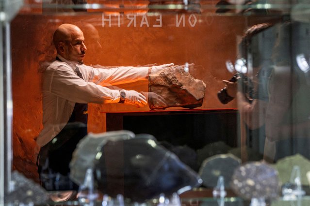 A handler is reflected on a showcase as he organizes meteorite NWA 16788, the largest known piece of Mars on Earth, during the press preview of Sotheby’s Natural History auction in New York City on July 8, 2025. (Photo by Eduardo Munoz/Reuters)