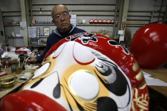 Japanese craftsman Sumikazu Nakata adds the final touches on a Daruma doll, which is believed to bring good luck, at his studio “Daimonya” in Takasaki, northwest of Tokyo November 23, 2014. (Photo by Yuya Shino/Reuters)