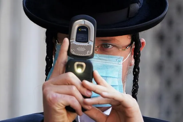 A Jewish man takes photos of a photographer while wearing a mask during the coronavirus disease (COVID-19) pandemic in the Borough Park section of the Brooklyn borough of New York City, New York, U.S., October 6, 2020. (Photo by Carlo Allegri/Reuters)