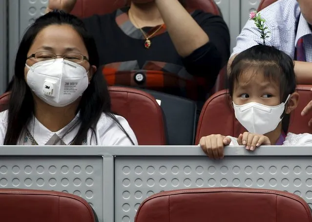 A girl and a woman wearing masks watch the women's singles match between China's Wang Qiang and Caroline Wozniacki of Denmark in a polluted day at the China Open tennis tournament in Beijing, China, October 6, 2015. (Photo by Kim Kyung-Hoon/Reuters)