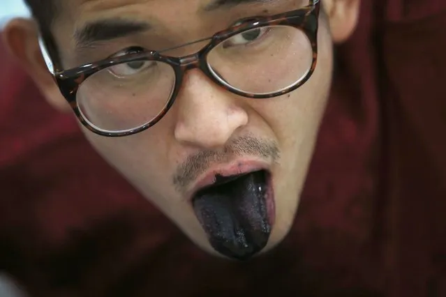 Folk artist Han Xiaoming demonstrates painting with his tongue in Hangzhou, Zhejiang province December 4, 2014. (Photo by Aly Song/Reuters)