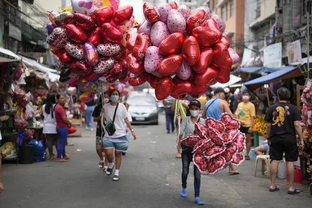 Women sell heart-shaped balloons at a flower market in Manila, Philippines on Monday, February 13, 2023. Prices of flowers have increased due to the high demand a day before Valentines Day. (Photo by Aaron Favila/AP Photo)