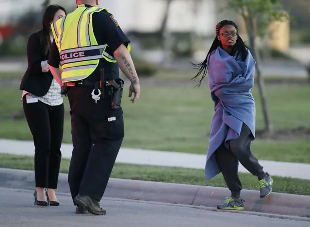 An employee wrapped in a blanket talks to a police officer after she was evacuated at a FedEx distribution center where a package exploded, Tuesday, March 20, 2018, in Schertz, Texas. Authorities believe the package bomb is linked to the recent string of Austin bombings. (Photo by Eric Gay/AP Photo)