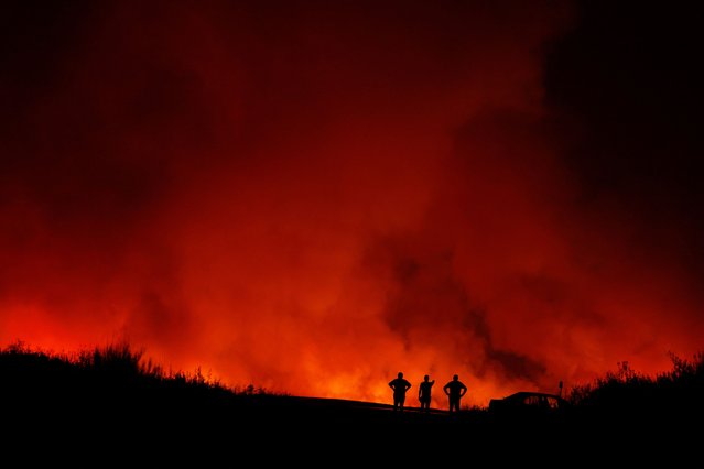 People are silhouetted as wildfire burns in Puercas, Spain, on August 11, 2025. (Photo by Susana Vera/Reuters)