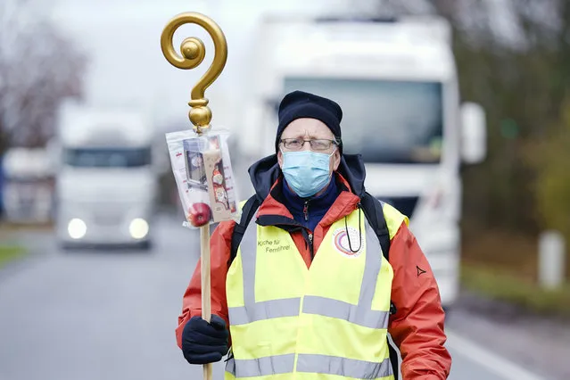 Pastor Michael Ohlemueller is standing at the motorway service station Wonnegau near Worms, Germany on December 5, 2020, with a crosier with chocolate Santa Claus and apple in a bag, which he wants to distribute as a gift to truck drivers. The action is intended as a thank you and appreciation for the drivers' work. (Photo by Uwe Anspach/dpa via AP Photo)