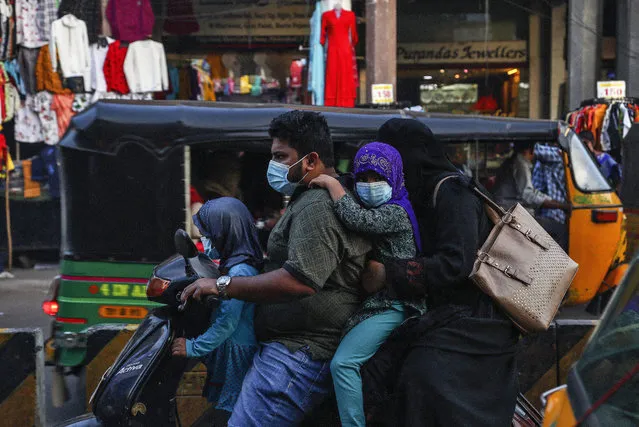 An Indian family wearing face masks as a precaution against the coronavirus rides on a scooter through a street in Hyderabad, India, Wednesday, December 9, 2020. India has more than 9 million cases of coronavirus, second behind the United States. (Photo by Mahesh Kumar A./AP Photo)