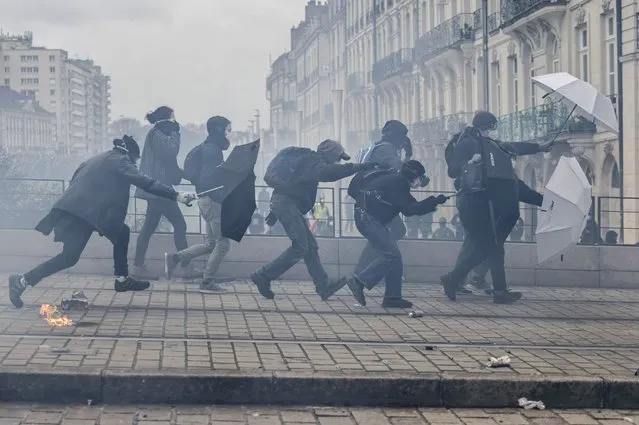 Protesters shield with umbrellas as they scuffle with riot police during rally in Nantes, western France, Thursday, March 23, 2023. French unions are holding their first mass demonstrations Thursday since President Emmanuel Macron enflamed public anger by forcing a higher retirement age through parliament without a vote. (Photo by Jeremias Gonzalez/AP Photo)