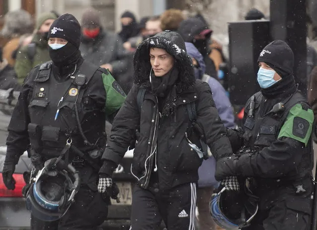 Police detain a person during a demonstration in Montreal, Sunday, December 20, 2020, where people protested measures implemented by the Quebec government to help stop the spread of COVID-19. The COVID-19 pandemic continues in Canada and around the world. (Photo by Graham Hughes/The Canadian Press via AP Photo)