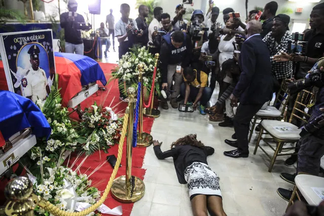 A woman cries on the floor next to the coffins holding the remains of three police officers who were killed in the line of duty during a wake at the Police Academy in Port-au-Prince, Haiti, Tuesday, January 31, 2023. The officers were killed in an ambush by gang members in the capital on Jan. 20. (Photo by Joseph Odelyn/AP Photo)