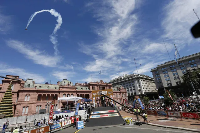 An airplane performs an acrobatic fly over the Casa Rosada Presidential Palace before the departure ceremony for Dakar Rally 2015 in Buenos Aires January 3, 2015. (Photo by Marcos Brindicci/Reuters)