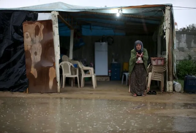 A Palestinian woman, whose house was destroyed by what witnesses said was Israeli shelling during the 50-day war in the summer of 2014, gestures as she stands at her makeshift shelter on a rainy day in Khan Younis in the southern Gaza Strip October 7, 2015. (Photo by Ibraheem Abu Mustafa/Reuters)