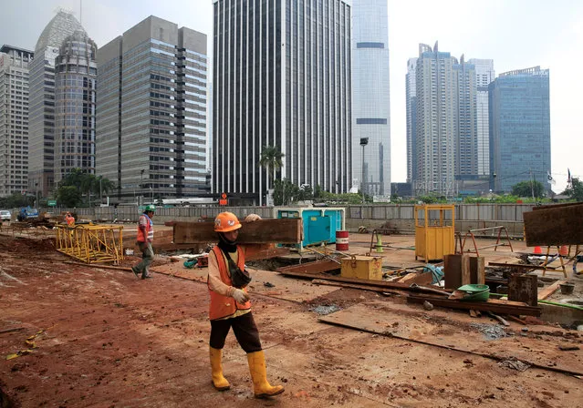 A worker carry pieces of wood as walks at the Jakarta Mass Rapid Transit construction at Sudirman Business District in Jakarta, Indonesia, April 17, 2018. (Photo by Reuters/Beawiharta)