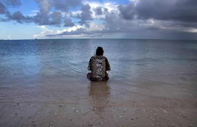 Binata Pinata scales a fish her husband Kaibakia caught, as she sits in the sea just off Bikeman islet, located off South Tarawa in the central Pacific island nation of Kiribati May 25, 2013. (Photo by David Gray/Reuters)