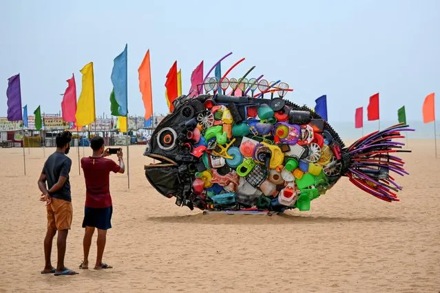 People take pictures of an installation depicting a fish, made from plastic wastes displayed at Edward Elliot's Beach to create awareness among locals ahead of the G20 meeting in Chennai on May 21, 2023. (Photo by R. Satish Babu/AFP Photo)