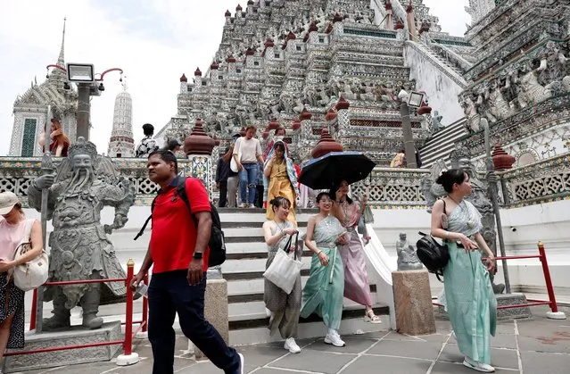 Foreign tourists and Chinese tourists dressed in Thai traditional costumes rented from a clothing rental shop visit Wat Arun or Temple of Dawn in Bangkok, Thailand, 22 May 2023. (Photo by Rungroj Yongrit/EPA/EFE)