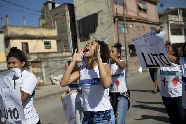 Students and friends of Marcos Vinicius, 14, who was shot to death during a civil police and military operation at the Mare slum, holding signs that read in Portuguese “Mourning” during a protest in Rio de Janeiro, Brazil, Thursday, June 21, 2018. Marcos Vinicius was walking to school when he was struck by a stray bullet in the stomach on Wednesday. At least six other people were killed during the police and military operation. (Photo by Silvia Izquierdo/AP Photo)